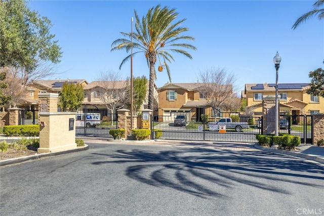 544 W Elm Park Ave, Rialto, CA 92376 - view of asphalt road featuring a residential view, curbs, a gate, street lights, and a gated entry