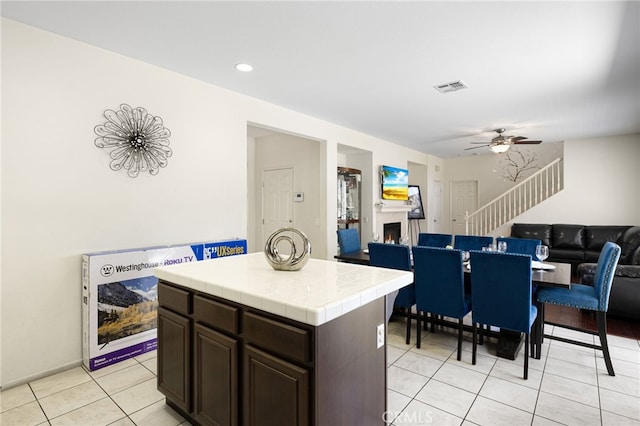 544 W Elm Park Ave, Rialto, CA 92376 - kitchen with tile countertops, a ceiling fan, light tile patterned floors, a warm lit fireplace, and open floor plan