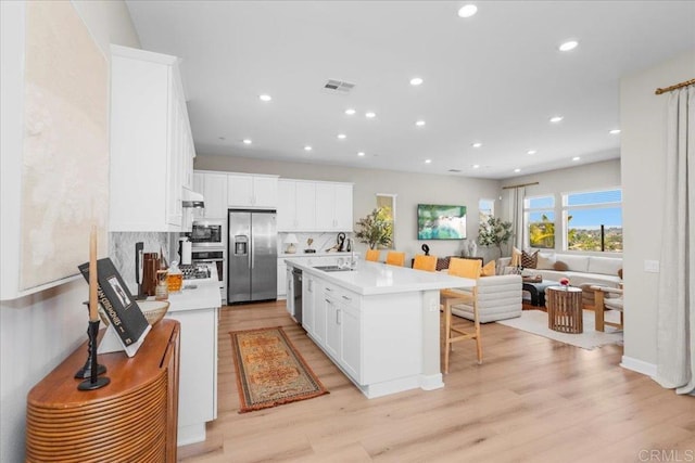 660 Westbrook Loop, San Marcos, CA 92078 - kitchen with stainless steel appliances, recessed lighting, light wood-style floors, a breakfast bar, and light countertops