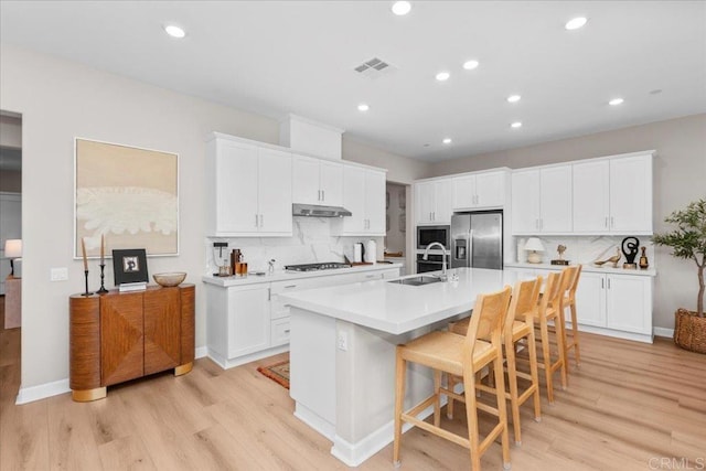 660 Westbrook Loop, San Marcos, CA 92078 - kitchen with stainless steel appliances, light wood-type flooring, backsplash, a kitchen island with sink, and recessed lighting