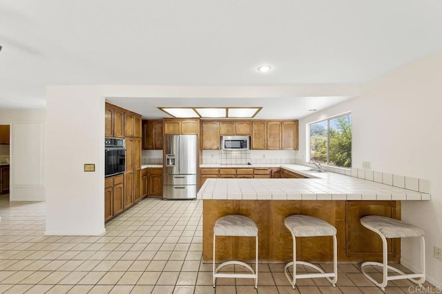 2239 Sunset Dr, Escondido, CA 92025 - kitchen with stainless steel appliances, a peninsula, tile counters, decorative backsplash, and light tile patterned floors