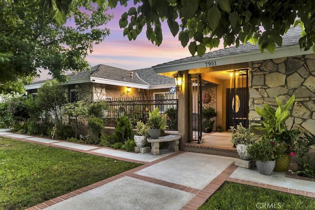 7951 Woodlake Ave, West Hills, CA 91304 - exterior entry at dusk featuring stone siding