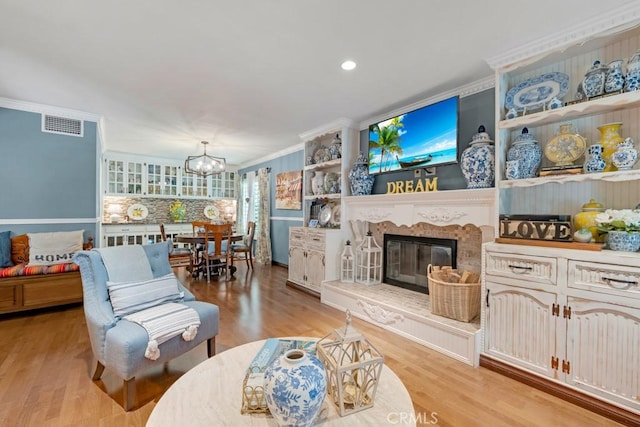 7951 Woodlake Ave, West Hills, CA 91304 - living area with a chandelier, light wood-style floors, crown molding, a glass covered fireplace, and recessed lighting