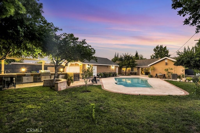 7951 Woodlake Ave, West Hills, CA 91304 - pool at dusk with exterior kitchen, a patio area, and a yard