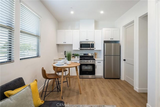 20109 Archwood St, Winnetka, CA 91306 - kitchen featuring stainless steel appliances, white cabinets, light wood finished floors, backsplash, and light countertops
