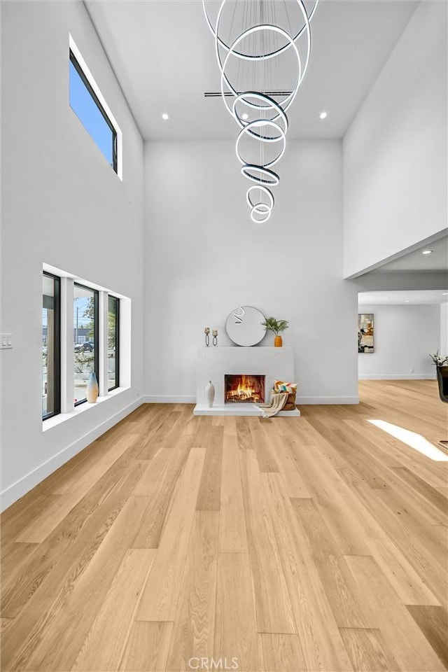 1027 N Lamer St, Burbank, CA 91506 - unfurnished living room with a high ceiling, light wood-type flooring, a lit fireplace, recessed lighting, and a chandelier