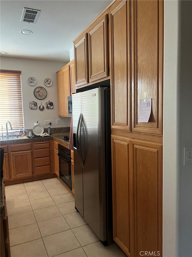 4630 Via Dulce, Camarillo, CA 93012 - kitchen with appliances with stainless steel finishes, dark countertops, light tile patterned floors, and brown cabinetry