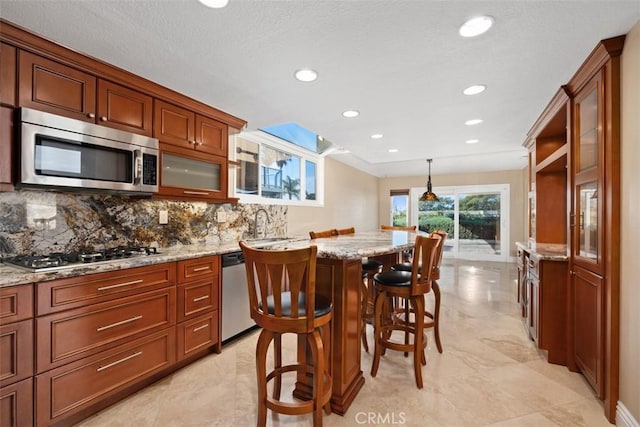 33551 Sandcastle Ct, Dana Point, CA 92629 - kitchen featuring appliances with stainless steel finishes, a breakfast bar area, backsplash, light stone counters, and a center island