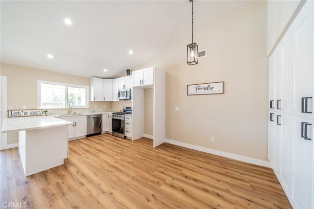 11617 Low Chaparral Dr, Victorville, CA 92392 - kitchen featuring appliances with stainless steel finishes, light wood-style floors, vaulted ceiling, a peninsula, and light countertops