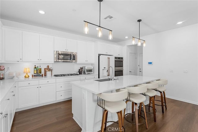 835 Orangedale Ave, Redlands, CA 92374 - kitchen with appliances with stainless steel finishes, dark wood finished floors, white cabinets, recessed lighting, and a kitchen bar