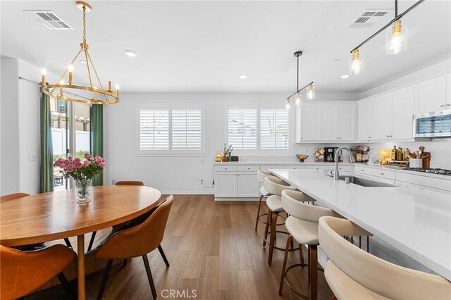 835 Orangedale Ave, Redlands, CA 92374 - kitchen with stainless steel microwave, a chandelier, wood finished floors, healthy amount of natural light, and recessed lighting