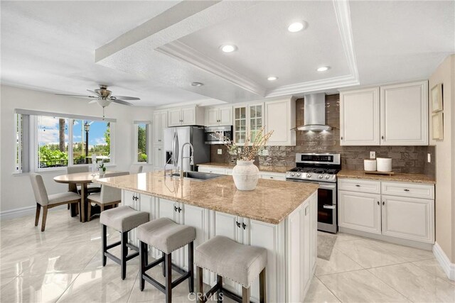 5999 Cedar Mountain Dr, Rancho Cucamonga, CA 91737 - kitchen with stainless steel appliances, wall chimney exhaust hood, a tray ceiling, tasteful backsplash, and a kitchen bar