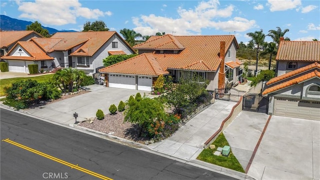 5999 Cedar Mountain Dr, Rancho Cucamonga, CA 91737 - mediterranean / spanish house with a gate, concrete driveway, a tiled roof, and a residential view