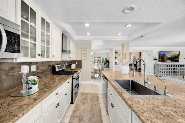 5999 Cedar Mountain Dr, Rancho Cucamonga, CA 91737 - kitchen with stainless steel appliances, a tray ceiling, tasteful backsplash, wall chimney exhaust hood, and glass insert cabinets
