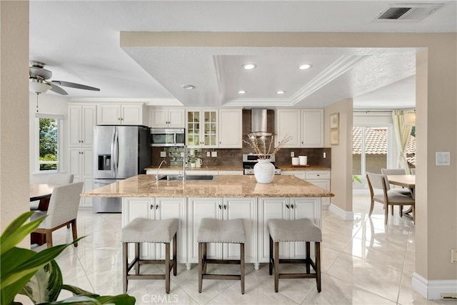 5999 Cedar Mountain Dr, Rancho Cucamonga, CA 91737 - kitchen featuring wall chimney range hood, stainless steel appliances, a raised ceiling, decorative backsplash, and a kitchen breakfast bar