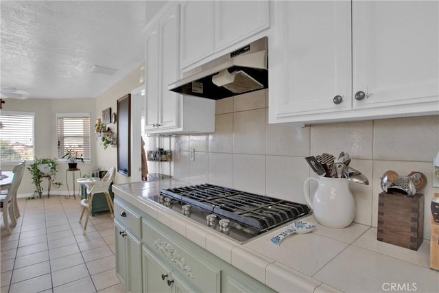 7330 Smoke Tree Rd, Phelan, CA 92371 - kitchen featuring under cabinet range hood, stainless steel gas stovetop, tile countertops, backsplash, and a textured ceiling