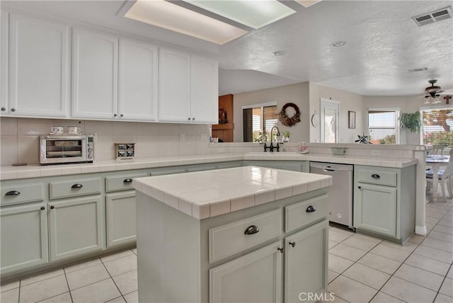 7330 Smoke Tree Rd, Phelan, CA 92371 - kitchen featuring dishwasher, a peninsula, light tile patterned flooring, a kitchen island, and a textured ceiling