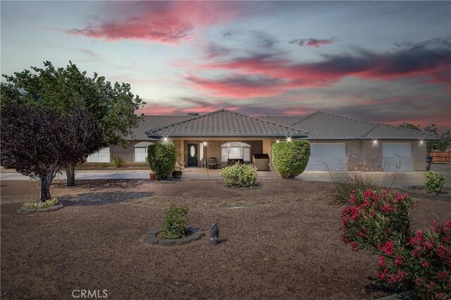 7330 Smoke Tree Rd, Phelan, CA 92371 - view of front of house with driveway, an attached garage, a tile roof, stucco siding, and covered porch