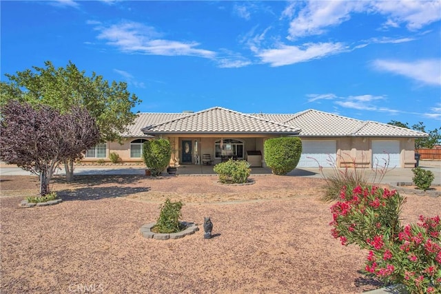 7330 Smoke Tree Rd, Phelan, CA 92371 - view of front of property with a tiled roof, concrete driveway, covered porch, a garage, and stucco siding