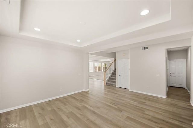 36845 Gemina Ave, Murrieta, CA 92563 - spare room featuring a tray ceiling, recessed lighting, stairs, and light wood finished floors