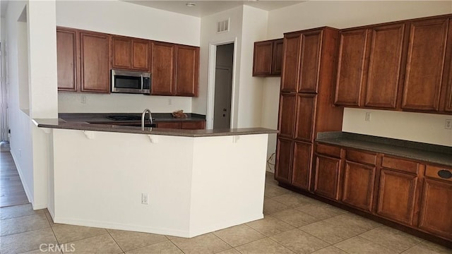 9019 Fremont Ct, Oak Hills, CA 92344 - kitchen with stainless steel microwave, dark countertops, and light tile patterned flooring
