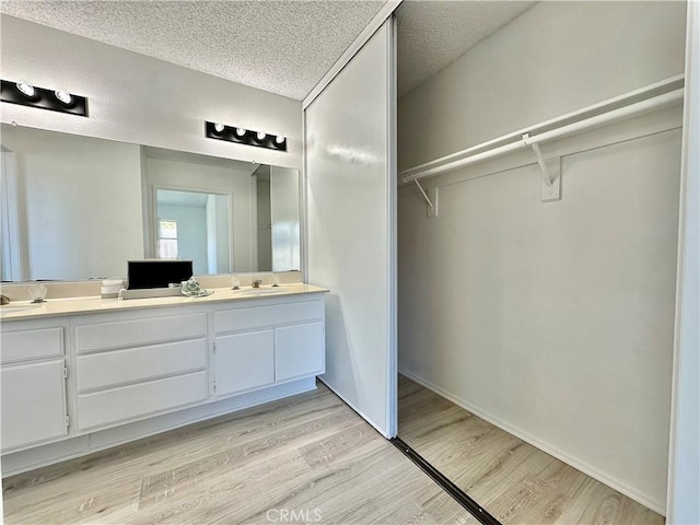 2568 Highgate Ct, Chino Hills, CA 91709 - bathroom featuring double vanity, wood finished floors, a walk in closet, and a textured ceiling