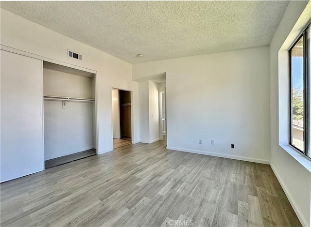 2568 Highgate Ct, Chino Hills, CA 91709 - unfurnished bedroom with light wood finished floors, multiple windows, a textured ceiling, and a closet