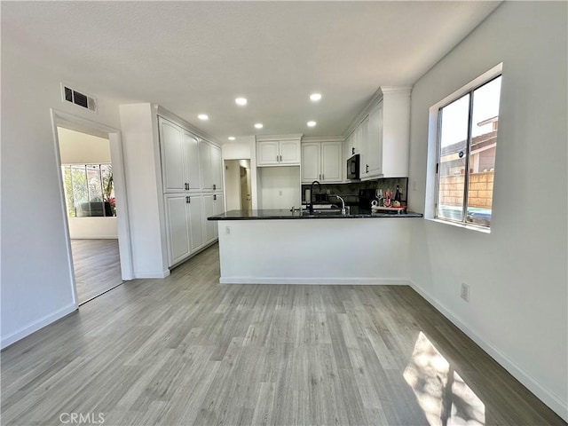 2568 Highgate Ct, Chino Hills, CA 91709 - kitchen with black microwave, a peninsula, white cabinets, dark countertops, and healthy amount of natural light