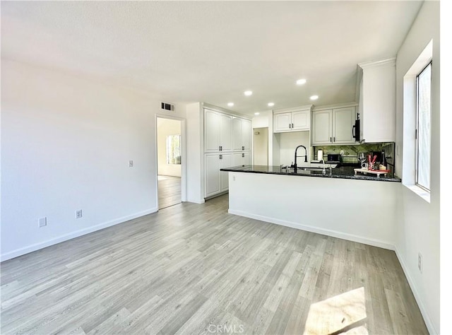 2568 Highgate Ct, Chino Hills, CA 91709 - kitchen with dark countertops, a peninsula, white cabinets, light wood-style floors, and decorative backsplash