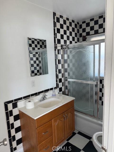 2208 W Olympic Blvd, Montebello, CA 90640 - full bath featuring tile patterned floors, vanity, bath / shower combo with glass door, and tile walls