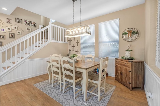 25525 Fitzgerald Ave, Stevenson Ranch, CA 91381 - dining space featuring wainscoting, light wood-style floors, stairway, and a decorative wall