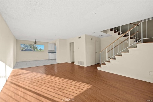 11331 Elliott Ave Unit 21, El Monte, CA 91732 - unfurnished living room featuring wood finished floors, stairs, a textured ceiling, and a chandelier