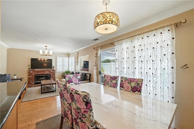 19121 Broken Bow Dr, Riverside, CA 92508 - dining space with ornamental molding, light wood-style flooring, a chandelier, and a fireplace