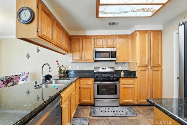 19121 Broken Bow Dr, Riverside, CA 92508 - kitchen with appliances with stainless steel finishes, dark stone countertops, light tile patterned floors, and a skylight