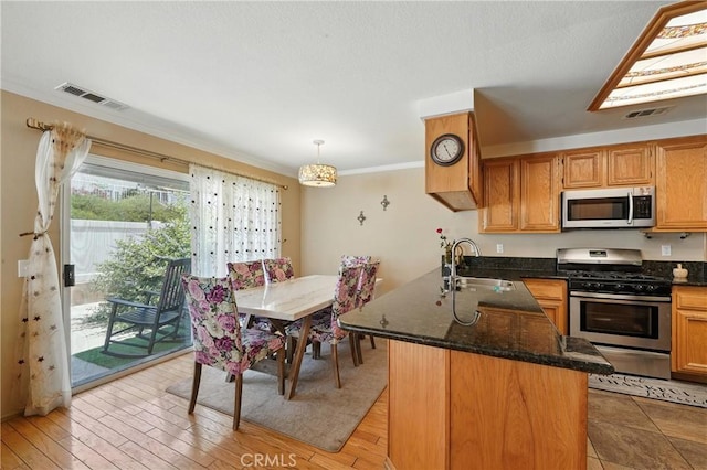 19121 Broken Bow Dr, Riverside, CA 92508 - kitchen with stainless steel appliances, a peninsula, crown molding, dark stone counters, and pendant lighting