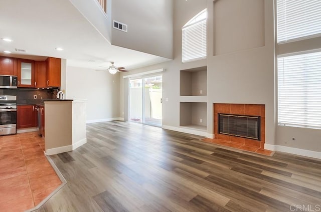 4620 Los Alamos Way Unit C, Oceanside, CA 92057 - unfurnished living room with a high ceiling, a tiled fireplace, light wood-type flooring, recessed lighting, and a ceiling fan