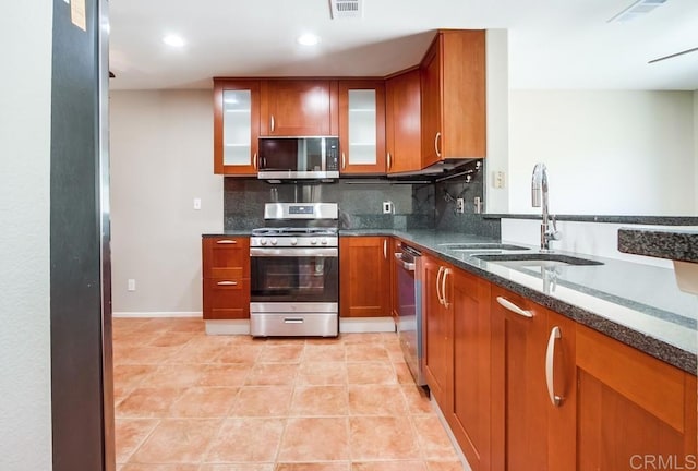 4620 Los Alamos Way Unit C, Oceanside, CA 92057 - kitchen featuring stainless steel appliances, backsplash, brown cabinetry, dark stone countertops, and glass insert cabinets