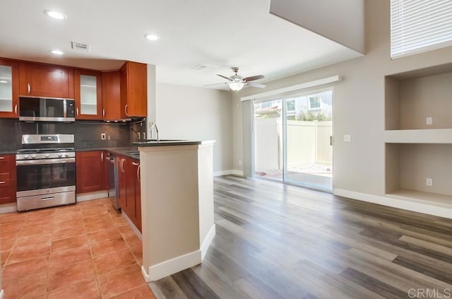 4620 Los Alamos Way Unit C, Oceanside, CA 92057 - kitchen featuring stainless steel appliances, dark countertops, a ceiling fan, decorative backsplash, and glass insert cabinets