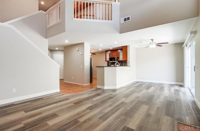 4620 Los Alamos Way Unit C, Oceanside, CA 92057 - unfurnished living room featuring a ceiling fan, light wood finished floors, recessed lighting, stairs, and a towering ceiling