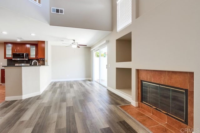4620 Los Alamos Way Unit C, Oceanside, CA 92057 - unfurnished living room with a tiled fireplace, a high ceiling, wood finished floors, a ceiling fan, and recessed lighting