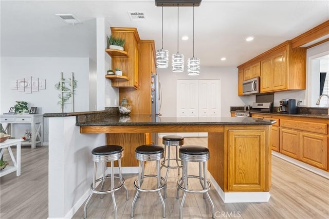 2951 S Plainfield Pl, Ontario, CA 91761 - kitchen featuring stainless steel appliances, open shelves, light wood-style flooring, a peninsula, and a breakfast bar