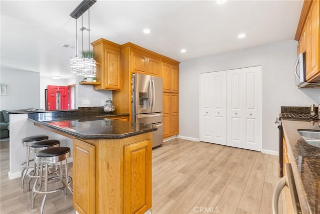 2951 S Plainfield Pl, Ontario, CA 91761 - kitchen with stainless steel appliances, a kitchen bar, light wood finished floors, brown cabinetry, and hanging light fixtures