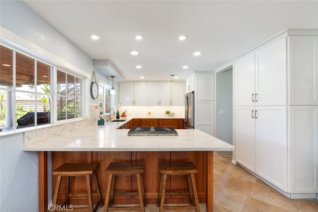 1225 Old Hickory Rd, Corona, CA 92882 - kitchen with stainless steel appliances, a peninsula, white cabinetry, a kitchen bar, and light tile patterned floors