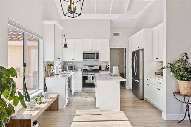 215 Meadowlark Rd, Paso Robles, CA 93446 - kitchen featuring appliances with stainless steel finishes, a high ceiling, light wood-style flooring, a kitchen island, and white cabinetry