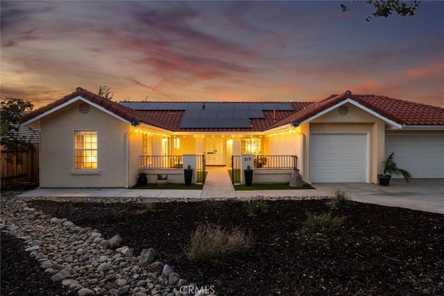 215 Meadowlark Rd, Paso Robles, CA 93446 - back of house at dusk with an attached garage, covered porch, solar panels, and concrete driveway
