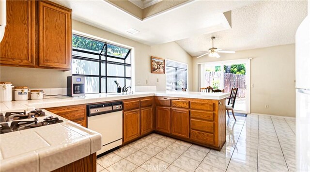 7339 Greenbriar Pl, Rancho Cucamonga, CA 91730 - kitchen featuring white appliances, brown cabinetry, tile counters, a peninsula, and lofted ceiling