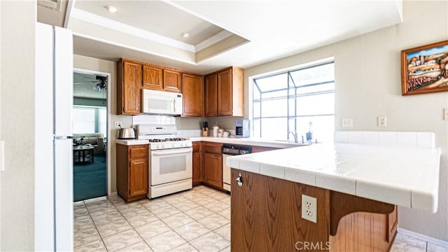7339 Greenbriar Pl, Rancho Cucamonga, CA 91730 - kitchen featuring white appliances, brown cabinets, a peninsula, a tray ceiling, and a breakfast bar