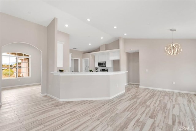 18420 Wisteria St, Hesperia, CA 92345 - kitchen featuring stainless steel microwave, white cabinetry, light countertops, light wood-style flooring, and high vaulted ceiling