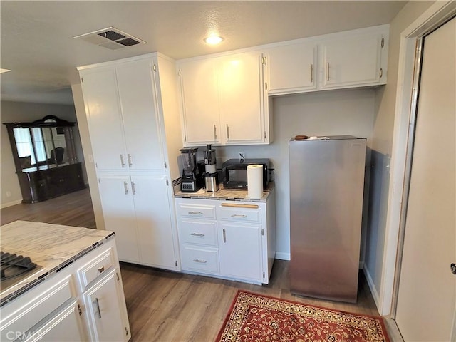 15420 Apache Rd, Apple Valley, CA 92307 - kitchen with light wood-type flooring, white cabinets, freestanding refrigerator, and light stone countertops