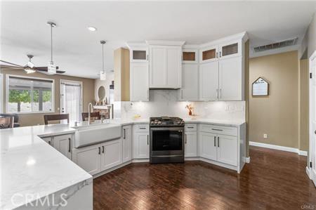 11126 Whitebark Ln, Corona, CA 92883 - kitchen featuring stainless steel gas stove, dark wood-type flooring, light countertops, a peninsula, and ceiling fan
